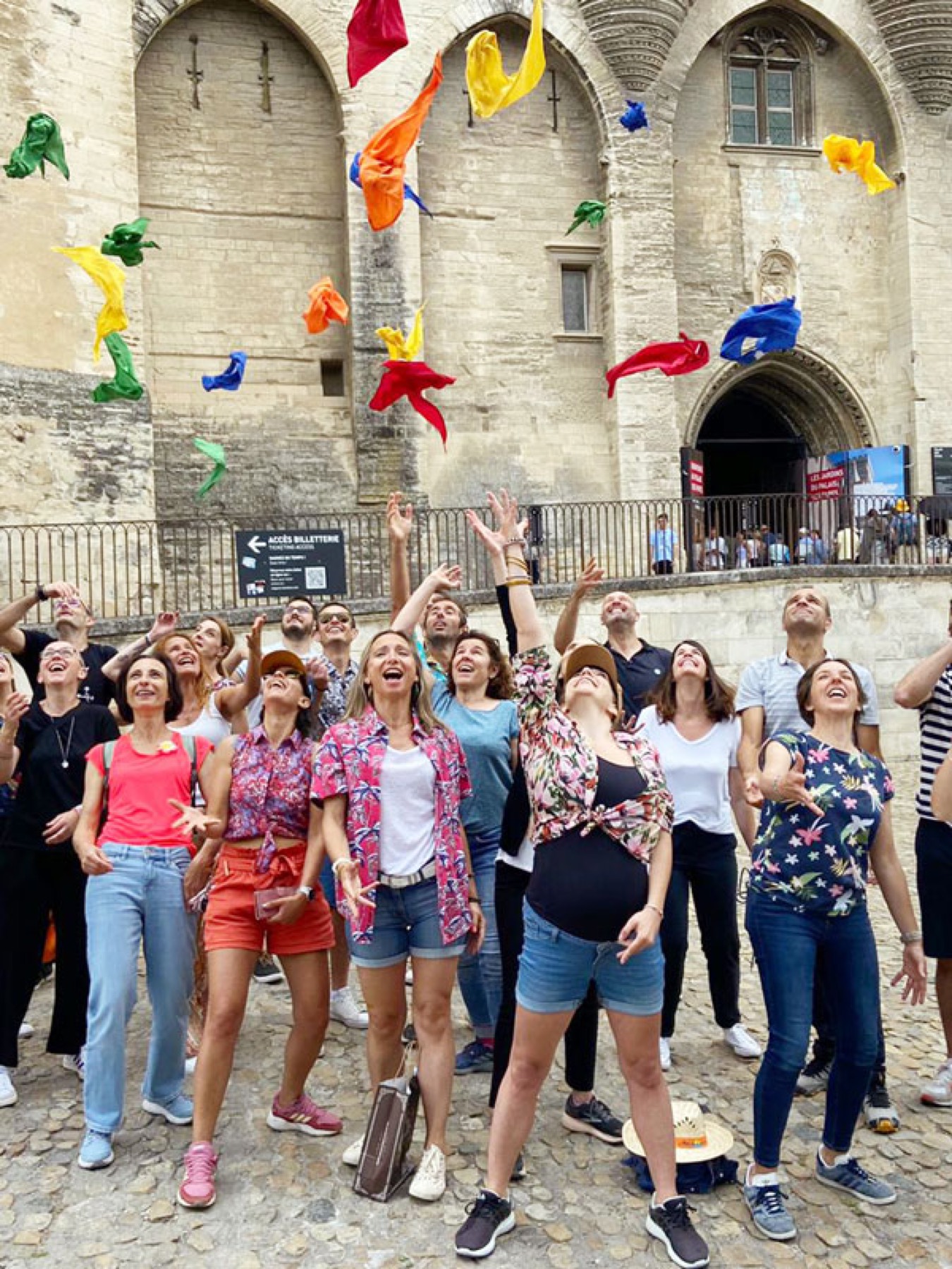 Des participantes lancent des foulards colorés devant un monument